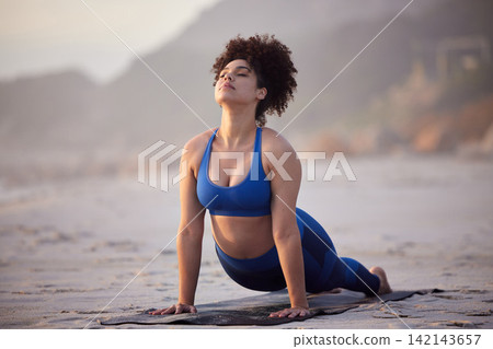 African woman, yoga and health for wellness at sea with peaceful mind, cobra pose and fitness. African person, zen and pilates workout at beach with stretching, spirituality and calm for mindset African woman, yoga and health for wellness at sea with peaceful mind, cobra pose and fitness. African person, zen and pilates workout at beach with stretching, spirituality and calm for mindset 142143657