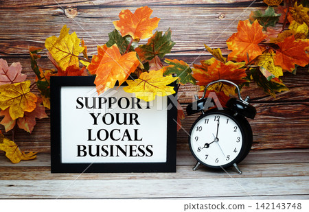 Support Your Local Business text with alarm clock on wooden background Support Your Local Business text with alarm clock on wooden background 142143748