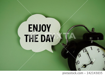 Enjoy The Day text on speech bubble with alarm clock on green background Enjoy The Day text on speech bubble with alarm clock on green background 142143835