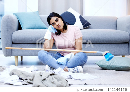 Woman, bored and portrait in living room for cleaning in house with sweeping, dirty clothes and broom. Annoyed, frustrated and moody from housework in home with unhappy for duties on weekend. 142144156
