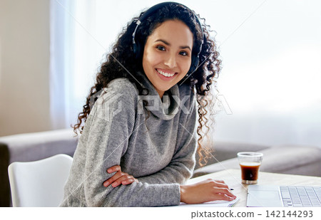 Portrait, headphones and happy woman in home office with laptop, coffee and research notes for freelance job. Music, streaming and girl at desk with notebook, computer and smile with remote work. Portrait, headphones and happy woman in home office with laptop, coffee and research notes for freelance job. Music, streaming and girl at desk with notebook, computer and smile with remote work. 142144293