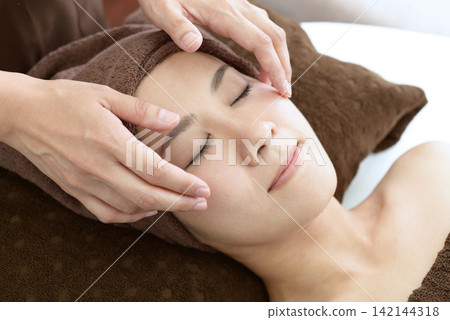 A woman receiving a facial massage A woman receiving a facial massage 142144318