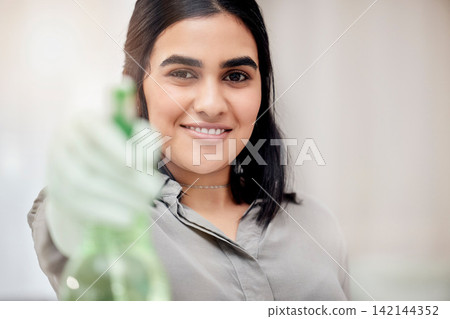 Woman, portrait and spray bottle for cleaning, dust and dirt by scrub in house. Middle Eastern housekeeper, happy and smile with detergent or disinfectant for housework, housekeeping and service 142144352