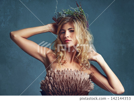 Portrait, beauty and woman with flower crown in hair at studio isolated on blue background. Face, wreath and hairstyle of confident person in makeup for skin, serious or natural cosmetic for fashion Portrait, beauty and woman with flower crown in hair at studio isolated on blue background. Face, wreath and hairstyle of confident person in makeup for skin, serious or natural cosmetic for fashion 142144353