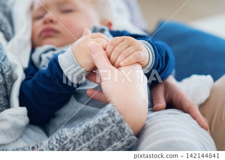 Mommy, baby and sleeping for holding hands in home, security and support in bonding for wellness. Mother, toddler and care for maternity or nap on couch, child development and comfort for single mom 142144841