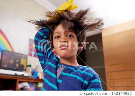 Little boy, portrait and chores with feather duster in living room for housekeeping, cleaning or duty at home. Face of Indian child or kid with gloves or brush for tidying, dust or furniture at house Little boy, portrait and chores with feather duster in living room for housekeeping, cleaning or duty at home. Face of Indian child or kid with gloves or brush for tidying, dust or furniture at house 142144923