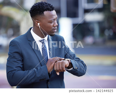 Watch, earphones and black man in city walking to work listening to music, radio or podcast. Time, serious and professional African male lawyer commuting to job with legal career in urban town. Watch, earphones and black man in city walking to work listening to music, radio or podcast. Time, serious and professional African male lawyer commuting to job with legal career in urban town. 142144925