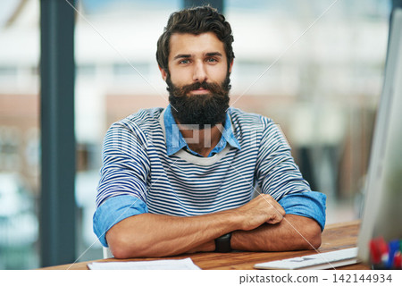 Portrait, creative and business man at desk in office by computer in startup company. Face, serious professional or confident entrepreneur, editor or employee working at table in Canada for career Portrait, creative and business man at desk in office by computer in startup company. Face, serious professional or confident entrepreneur, editor or employee working at table in Canada for career 142144934