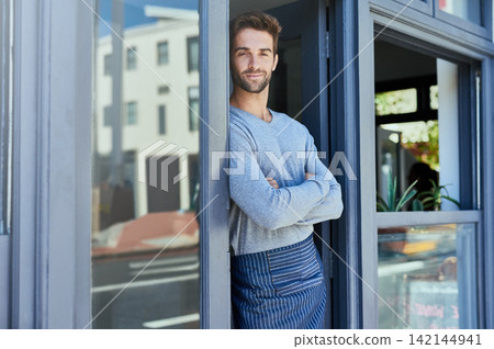 Door, crossed arms and portrait of barista by coffee shop with positive, happy and confident attitude. Smile, pride and man waiter standing by cafe or restaurant entrance for welcome in hospitality. Door, crossed arms and portrait of barista by coffee shop with positive, happy and confident attitude. Smile, pride and man waiter standing by cafe or restaurant entrance for welcome in hospitality. 142144941