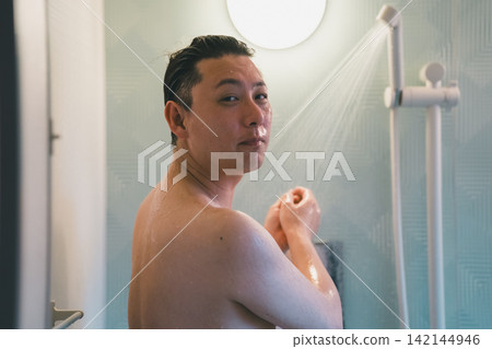 一位40歲男子洗澡時,正在淋浴間清洗身體。 一位40歲男子洗澡時,正在淋浴間清洗身體。 142144946