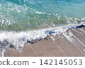 Crystal-clear emerald-green waves crashing against the sandy beach 142145053