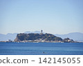 Enoshima Island floating in the blue Sagami Bay and the Sea Candle towering on the mountaintop. 142145055