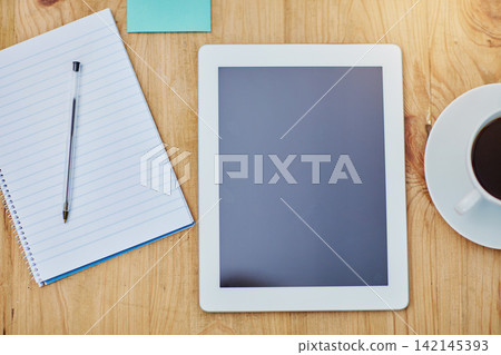 High angle, desk and tablet or paper in zoom with coffee, workspace with technology for background. Notebook, epad and above on table with drink in closeup, internet or app for marketing business High angle, desk and tablet or paper in zoom with coffee, workspace with technology for background. Notebook, epad and above on table with drink in closeup, internet or app for marketing business 142145393