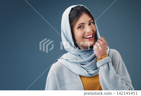 Woman, studio and smile with hijab in portrait with happy for confidence for islamic culture. Faith, beauty and pride with blue background for arab people with religion, middle east and natural 142145451