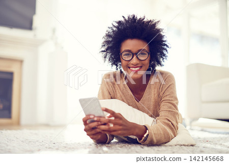 Black woman, portrait and afro with phone on living room floor for social media, blog or reading news at home. African, female person or freelancer on mobile smartphone for communication at house Black woman, portrait and afro with phone on living room floor for social media, blog or reading news at home. African, female person or freelancer on mobile smartphone for communication at house 142145668