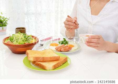 A woman eating breakfast A woman eating breakfast 142145686