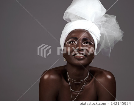 Thinking, wrap and black woman with makeup, smile and beauty in studio on grey background. Fashion, turban or African model with traditional outfit, eyeshadow cosmetics or necklace for culture pride Thinking, wrap and black woman with makeup, smile and beauty in studio on grey background. Fashion, turban or African model with traditional outfit, eyeshadow cosmetics or necklace for culture pride 142145934