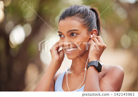 Fitness, earphones and Indian woman in park for running, training or morning cardio with music. Sports, smile and happy runner in forest for exercise, workout and streaming podcast for run motivation Fitness, earphones and Indian woman in park for running, training or morning cardio with music. Sports, smile and happy runner in forest for exercise, workout and streaming podcast for run motivation 142145961