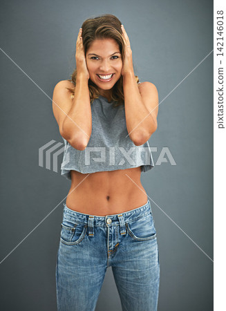 Woman, portrait and covered ears with studio, excitement and celebration for winner. Model, smile and happiness for good news, promotion and achievement with victory isolated on grey background Woman, portrait and covered ears with studio, excitement and celebration for winner. Model, smile and happiness for good news, promotion and achievement with victory isolated on grey background 142146018