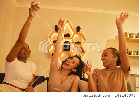 Friends, relax and drinking alcohol in home at night with excited energy or freedom together. Party, shots and woman in living room with fun social celebration on holiday, weekend or vacation Friends, relax and drinking alcohol in home at night with excited energy or freedom together. Party, shots and woman in living room with fun social celebration on holiday, weekend or vacation 142146045