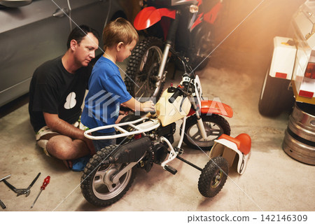 Parent, child and fixing bike in garage at home for teamwork, support and repair with tools. Family man, father and son for bonding, helping and together as mechanic for motorbike in carport Parent, child and fixing bike in garage at home for teamwork, support and repair with tools. Family man, father and son for bonding, helping and together as mechanic for motorbike in carport 142146309