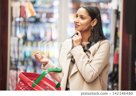 Happy woman, thinking and grocery shopping with basket for choice on ingredients, food or stock at supermarket. Female person, consumer or shopper with smile or cart in wonder or decision at store Happy woman, thinking and grocery shopping with basket for choice on ingredients, food or stock at supermarket. Female person, consumer or shopper with smile or cart in wonder or decision at store 142146480