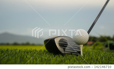 Golf clubs and balls on a green lawn in a beautiful golf course with morning sunshine. Golf clubs and balls on a green lawn in a beautiful golf course with morning sunshine. 142146710