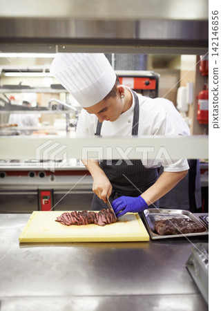 Professional, chef and man cutting meat, restaurant and cook staff and gourmet meal prep. Serious, catering and culinary skills for fine dining, nutrition and hospitality industry with busy employee Professional, chef and man cutting meat, restaurant and cook staff and gourmet meal prep. Serious, catering and culinary skills for fine dining, nutrition and hospitality industry with busy employee 142146856
