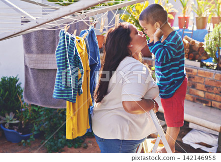 Mother, child and love for hanging washing with kiss or funny face with laundry housework, backyard or chore. Woman, son and ladder in garden or learning responsibility with help, teaching or hygiene Mother, child and love for hanging washing with kiss or funny face with laundry housework, backyard or chore. Woman, son and ladder in garden or learning responsibility with help, teaching or hygiene 142146958