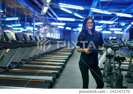 Portrait, girl and personal trainer at gym, clipboard and fitness, instructor and check list or schedule, workout and consulting with wellness, exercise and sports in active, coach and glasses Portrait, girl and personal trainer at gym, clipboard and fitness, instructor and check list or schedule, workout and consulting with wellness, exercise and sports in active, coach and glasses 142147270