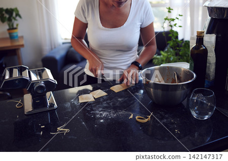 Hands, home and knife on pasta for baking food, meal prep and healthy lunch for nutrition in kitchen. Chef, cutting and woman with homemade Italian ravioli, flour and cooking wheat dough for dinner Hands, home and knife on pasta for baking food, meal prep and healthy lunch for nutrition in kitchen. Chef, cutting and woman with homemade Italian ravioli, flour and cooking wheat dough for dinner 142147317