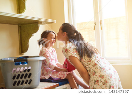 Kiss, mother and girl with clothes for laundry for washing in house, apartment or home for housekeeping and cleanliness. Basket, portrait or happy for chores, working and hygiene or maintenance Kiss, mother and girl with clothes for laundry for washing in house, apartment or home for housekeeping and cleanliness. Basket, portrait or happy for chores, working and hygiene or maintenance 142147597