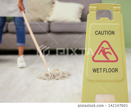 Person, mopping and caution sign for wet floor, slippery and housekeeping maintenance for hygiene or disinfecting. housekeeper, cleaning and hospitality service in living room of home with warning. Person, mopping and caution sign for wet floor, slippery and housekeeping maintenance for hygiene or disinfecting. housekeeper, cleaning and hospitality service in living room of home with warning. 142147601