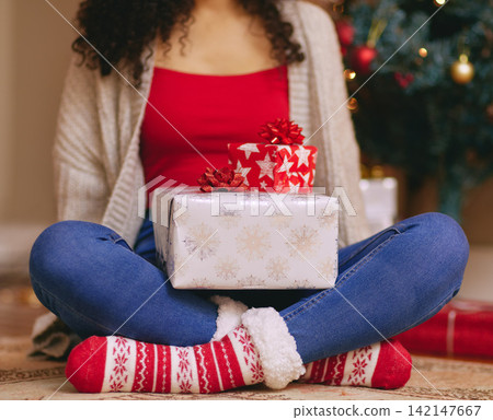 Christmas, package and person with gift on holiday or giving a present on vacation. Home, celebration and ribbon on box with surprise, giveaway or gratitude for offering closeup on xmas morning 142147667