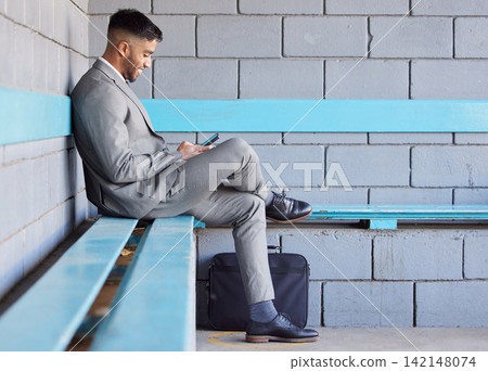 Business man, phone and bench at station for travel, check train schedule and browse on app in outdoors. Male person, relax and employee for commute to work, typing and internet for ticket website 142148074