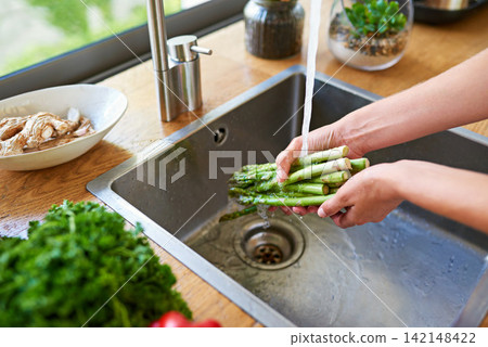 Cooking, hands and woman washing vegetables for meal prep, fresh and healthy food for lunch. Diet, wellness and person at kitchen sink with ingredients, nutrition and cleaning salad in water at home Cooking, hands and woman washing vegetables for meal prep, fresh and healthy food for lunch. Diet, wellness and person at kitchen sink with ingredients, nutrition and cleaning salad in water at home 142148422
