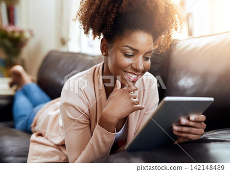Woman, couch and home or happy on tablet, relax and internet communication or social media scrolling. Reading, text and blog or online networking, meme and funny on tech on sofa in apartment Woman, couch and home or happy on tablet, relax and internet communication or social media scrolling. Reading, text and blog or online networking, meme and funny on tech on sofa in apartment 142148489