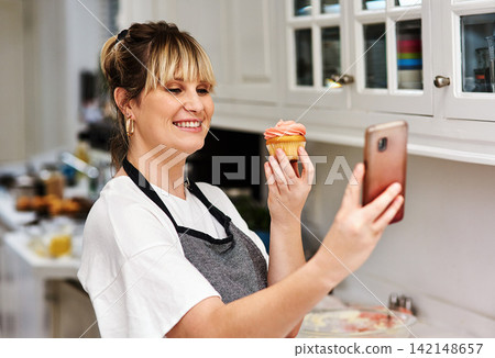 Baker, happy woman and selfie of dessert in kitchen for social media, show sweets and online blog post in home. Pastry, cupcake and photography of food chef and smile of influencer cooking in house Baker, happy woman and selfie of dessert in kitchen for social media, show sweets and online blog post in home. Pastry, cupcake and photography of food chef and smile of influencer cooking in house 142148657