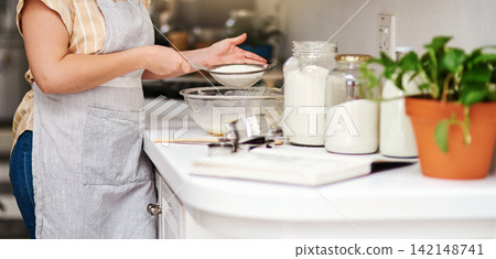 Woman, kitchen and sifting for flour, home and glass bowl for dessert or small business. Baker, ingredients and mixing with spatula, house or startup bakery for recipe prepare and sweet food process Woman, kitchen and sifting for flour, home and glass bowl for dessert or small business. Baker, ingredients and mixing with spatula, house or startup bakery for recipe prepare and sweet food process 142148741