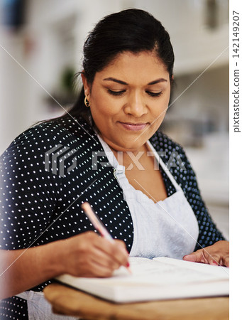 Book, baker and woman writing recipes for small business startup bakery at home for hobby. Smile, kitchen and mature female person with notes for dessert ingredients and baking process at apartment. Book, baker and woman writing recipes for small business startup bakery at home for hobby. Smile, kitchen and mature female person with notes for dessert ingredients and baking process at apartment. 142149207