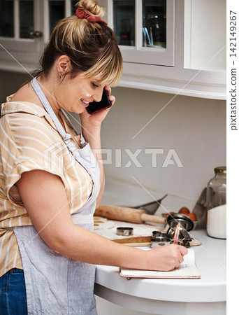Woman, cooking or writing with phone call for recipe, talking or meal ingredients in kitchen or home. Notebook, chef or happy baker with smile in discussion, communication or conversation on mobile Woman, cooking or writing with phone call for recipe, talking or meal ingredients in kitchen or home. Notebook, chef or happy baker with smile in discussion, communication or conversation on mobile 142149267