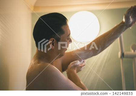 A middle-aged man washing his arms and armpits with body soap. A middle-aged man washing his arms and armpits with body soap. 142149833