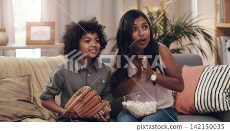 Child, mother and couch for watching baseball game with popcorn, glove and support for sports team. Mom, young boy and streaming sport channel in home with excited, television and competition on tv Child, mother and couch for watching baseball game with popcorn, glove and support for sports team. Mom, young boy and streaming sport channel in home with excited, television and competition on tv 142150035