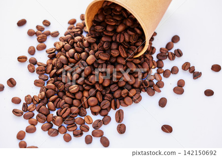 Coffee beans, top view and table closeup in studio isolated on a white background or backdrop. Above, caffeine and roast grain in cup for natural breakfast, organic latte or espresso in the morning Coffee beans, top view and table closeup in studio isolated on a white background or backdrop. Above, caffeine and roast grain in cup for natural breakfast, organic latte or espresso in the morning 142150692