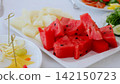 Fresh watermelon and cantaloupe slices garnishing white ceramic plate, presenting colorful summer fruit arrangement ready for casual dining or refreshing snack 142150723