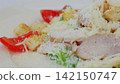 Grilled chicken caesar salad highlighting crisp romaine, golden croutons, ripe tomatoes, and freshly grated parmesan in vibrant culinary composition 142150747
