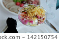 Russian salad - olivier - in glass, garnished with crispy potato straws, served during catering event with charcuterie plate blurring background 142150754