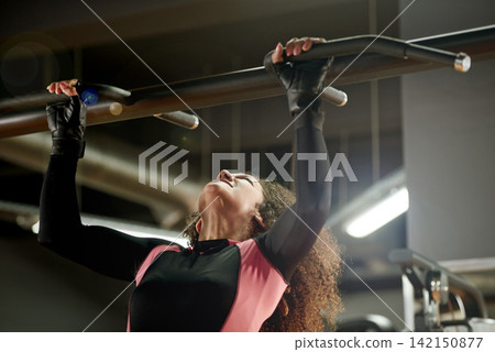 Training, woman and pull up exercise at gym on bar for muscle, wellness or healthy body. Chin up, fitness and strong female person with equipment at club for power, workout and sports for bodybuilder 142150877