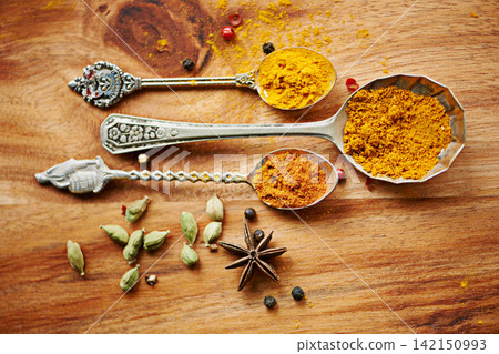 Spoons, spice and selection of seasoning for gourmet on kitchen table, turmeric and cardamom for meal. Top view, cooking and options for spicy diet in Indian culture, art and food preparation Spoons, spice and selection of seasoning for gourmet on kitchen table, turmeric and cardamom for meal. Top view, cooking and options for spicy diet in Indian culture, art and food preparation 142150993