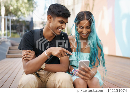 Couple, earphones and laughing with mobile phone for funny meme, comic or watching video on campus. Headphones, Indian man and woman with smartphone for social media, online app or web browsing Couple, earphones and laughing with mobile phone for funny meme, comic or watching video on campus. Headphones, Indian man and woman with smartphone for social media, online app or web browsing 142151074